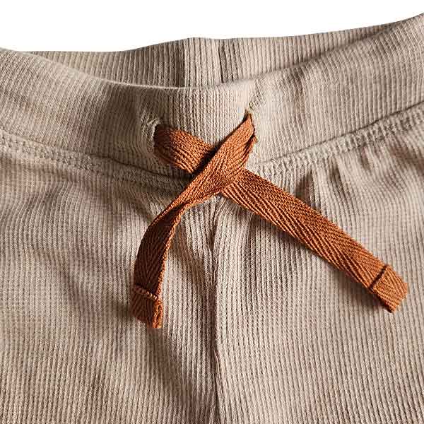 Studio Spruitje tweedehands babybroekje beige ribstof met bruin striklint en omslagboorden.